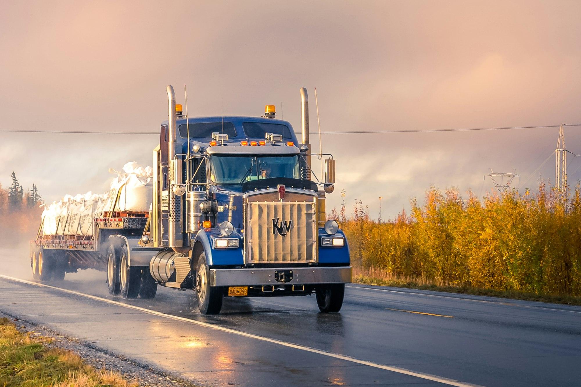 Blue semi truck on a highway at golden hour