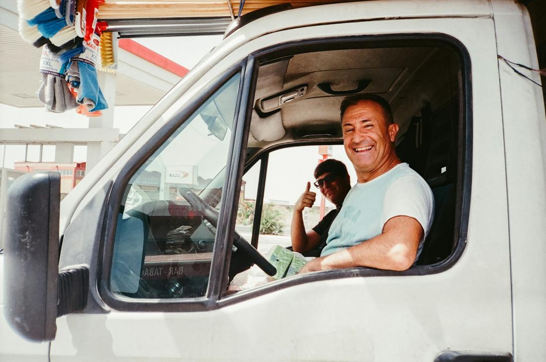 Smiling driver in his cab with a co-driver giving a thumbs up